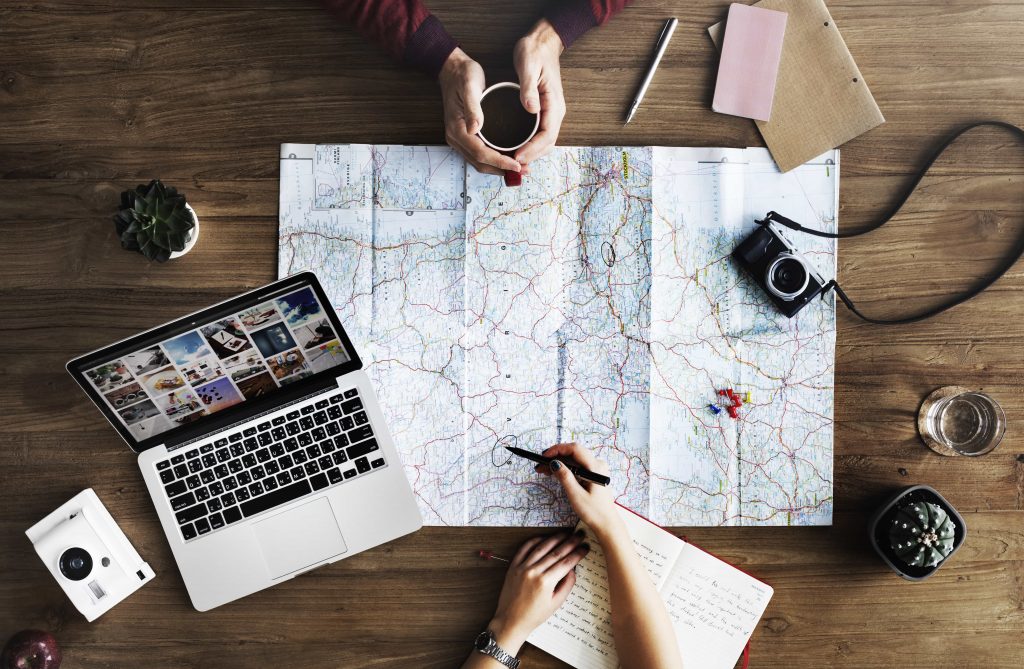Planowanie wyjazdu z mapą, laptopem i kawą